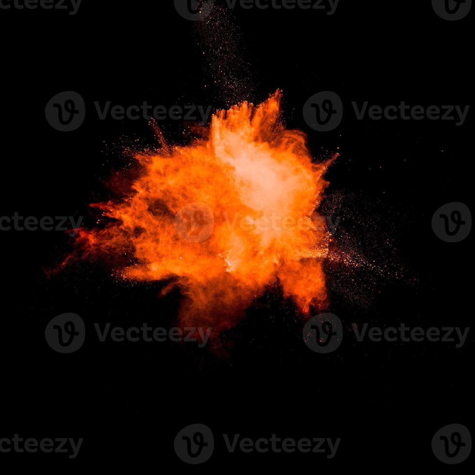 Orange powder explosion on black background. Orange color dust splash. photo