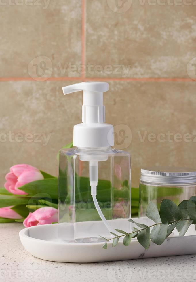 Transparent plastic container with a dispenser on the table. Bottle for liquid soap, shampoo photo