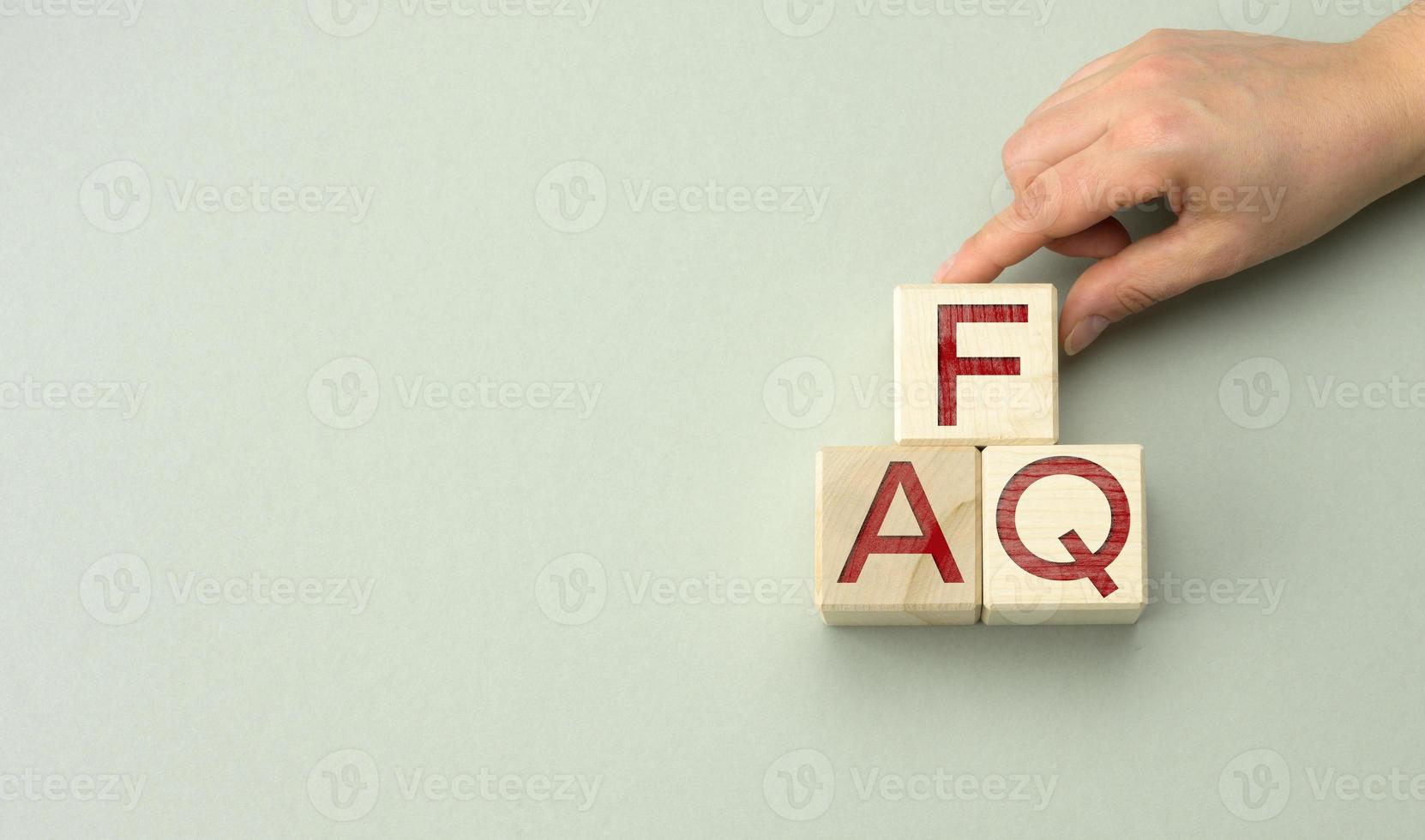 inscription FAQ frequently asked questions on wooden blocks on a gray background. QA concept, help and tips photo