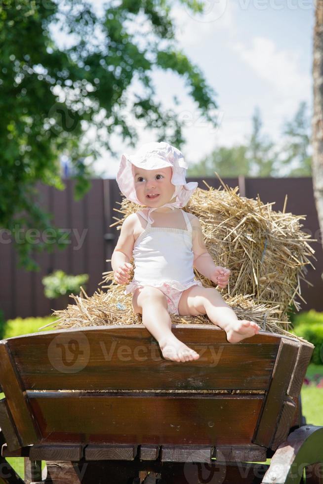 linda pequeño niña sentado en un carro foto