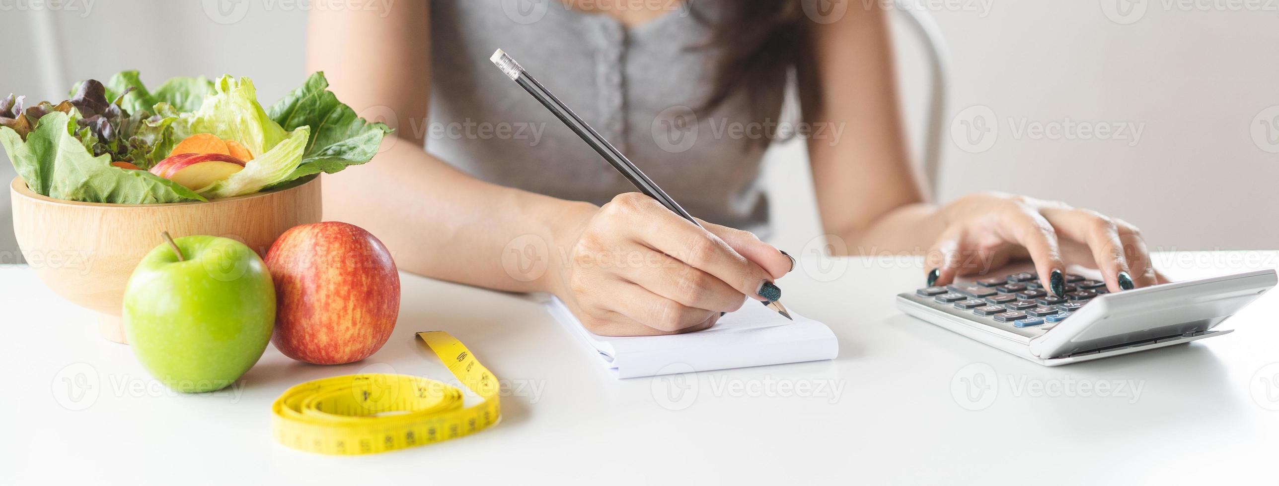 Woman calculating calories in her meal and taking note. photo