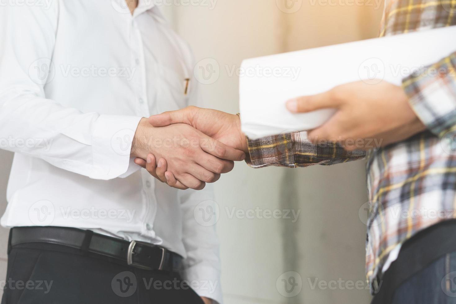 construction worker and contractor. Client shaking hands with team builder in renovation site. photo