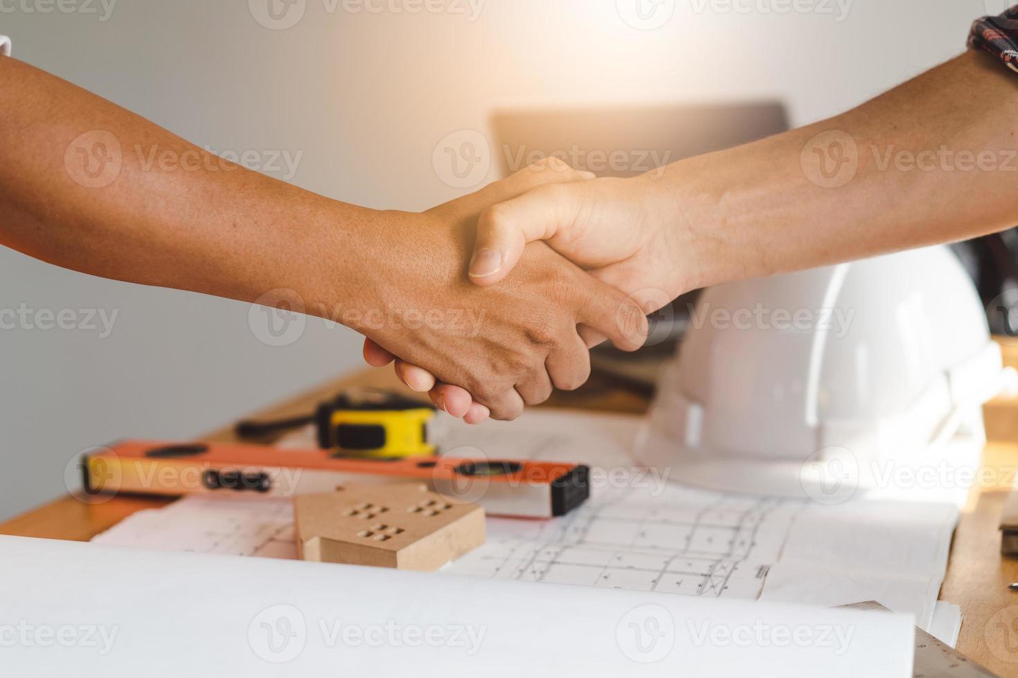 Successful deal, male architect shaking hands with client in construction site after confirm blueprint for renovate building. photo
