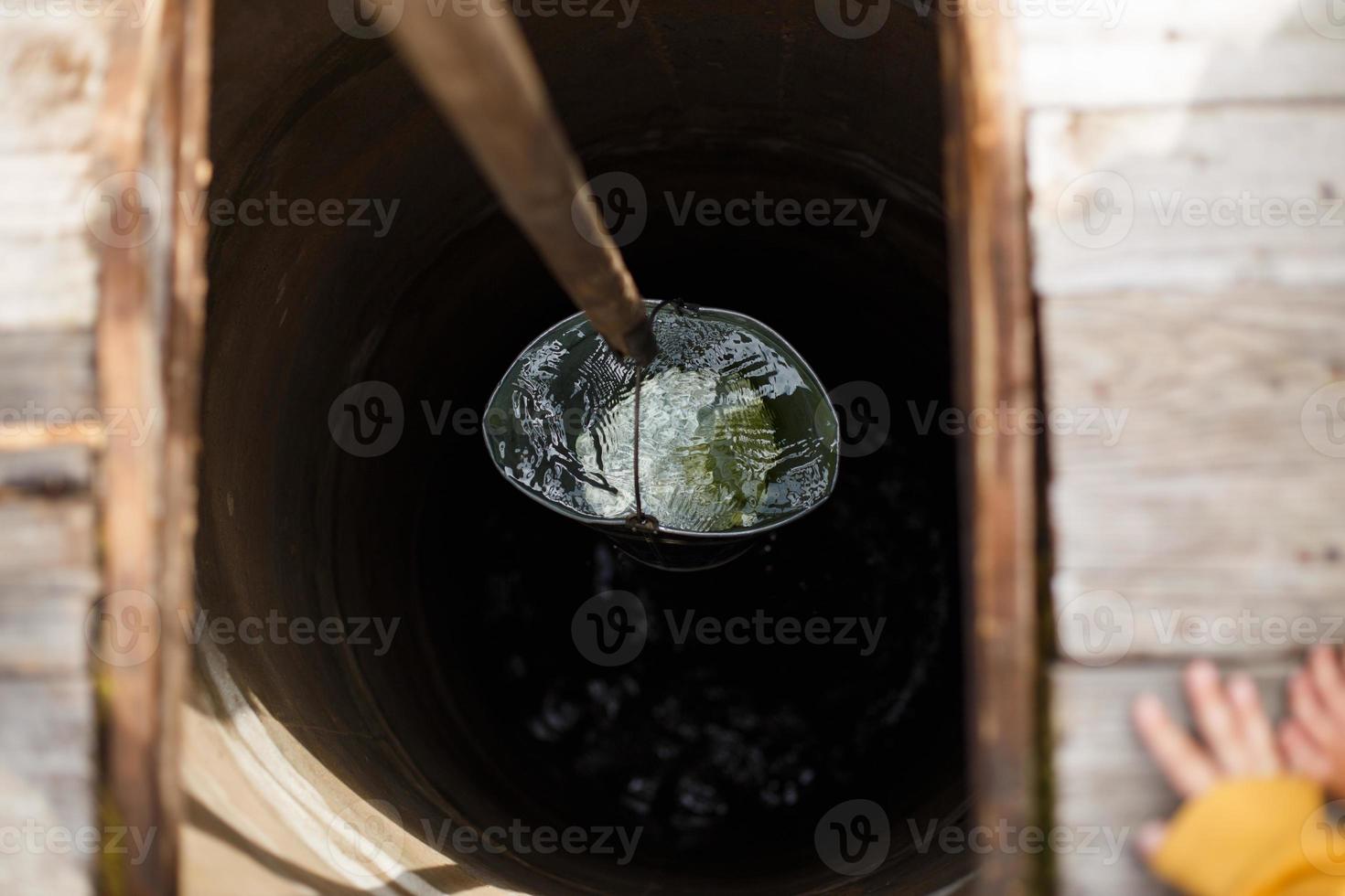 Blue bucked inside water well. A water well with an old iron bucket photo