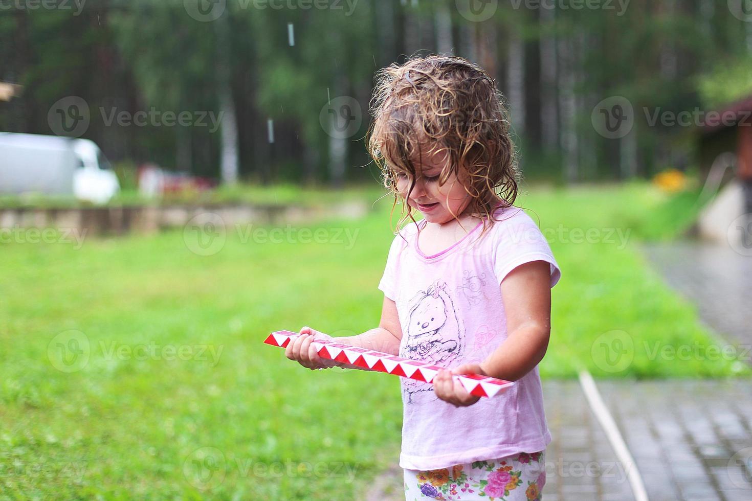 Adorable girl walking with toy at rainy day photo