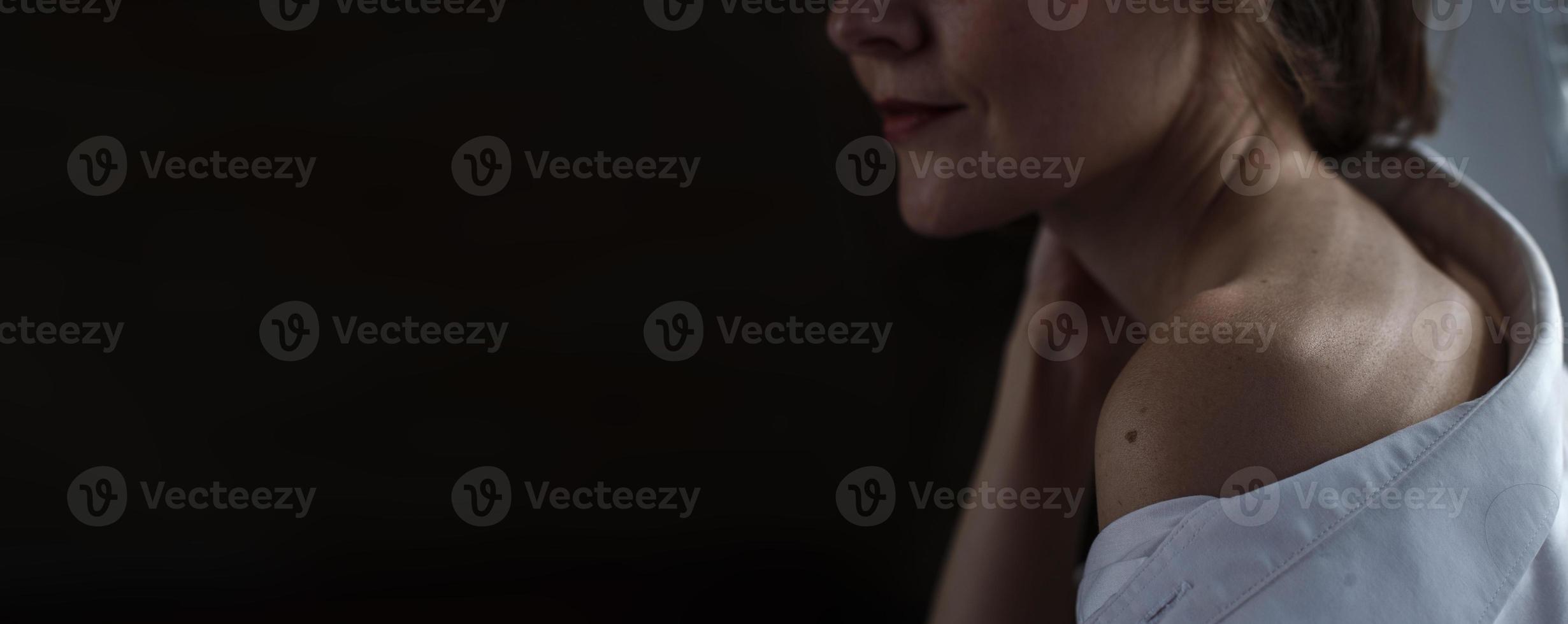 Sensual close up portrait of beautiful young lady relaxing at the window. female shoulder close up. hard shadows. banner photo