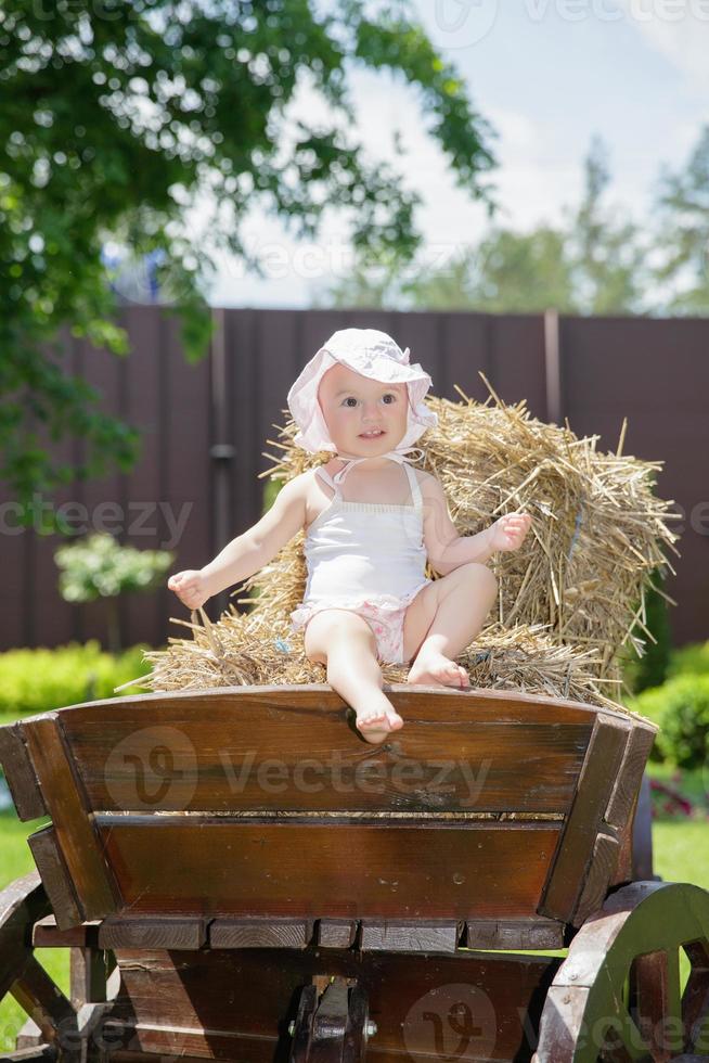 Happy little girl sitting on a carriage photo
