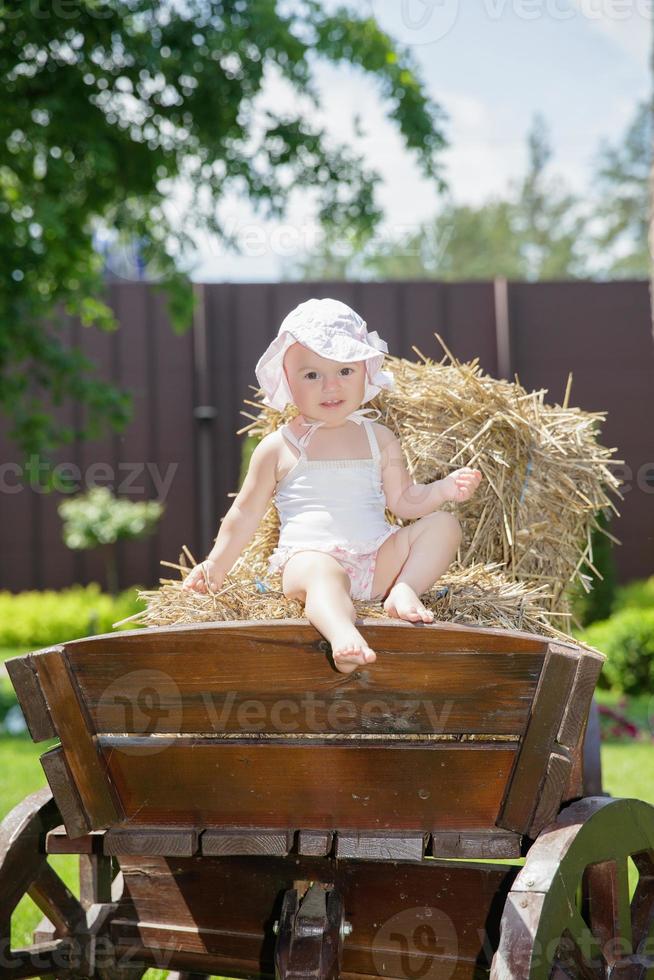 Beautiful little girl sitting on a carriage photo