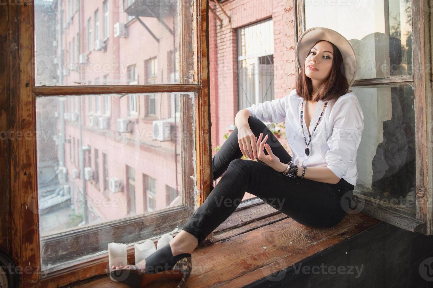 Pretty lady is sitting near the window photo