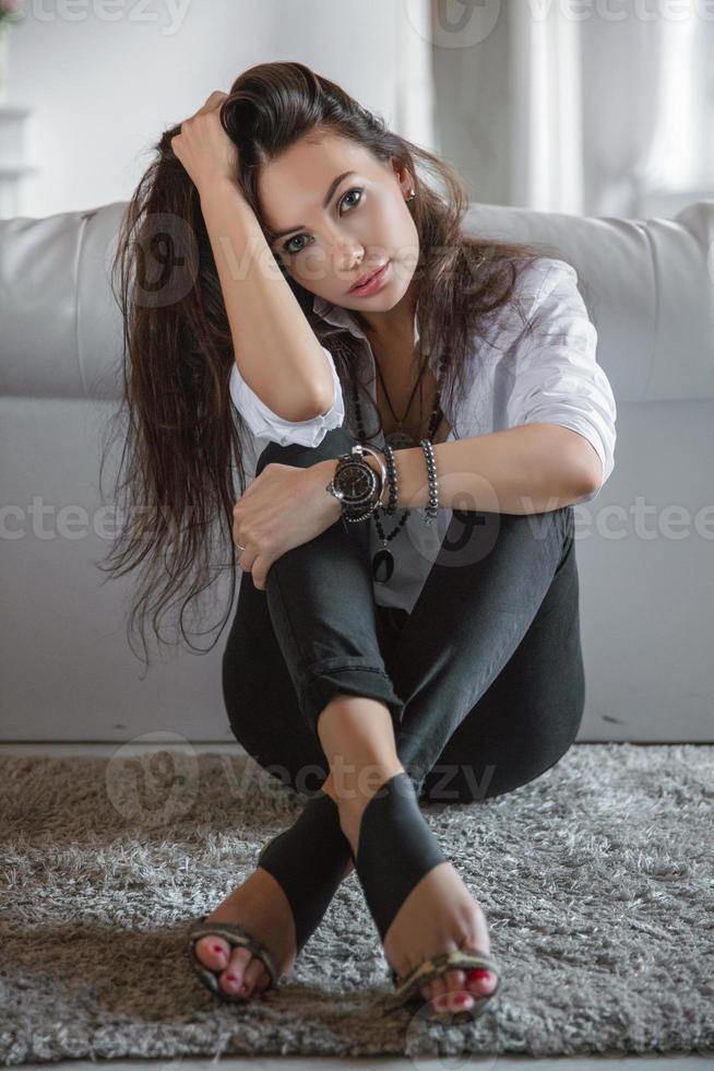 Pretty young woman sitting by the sofa photo