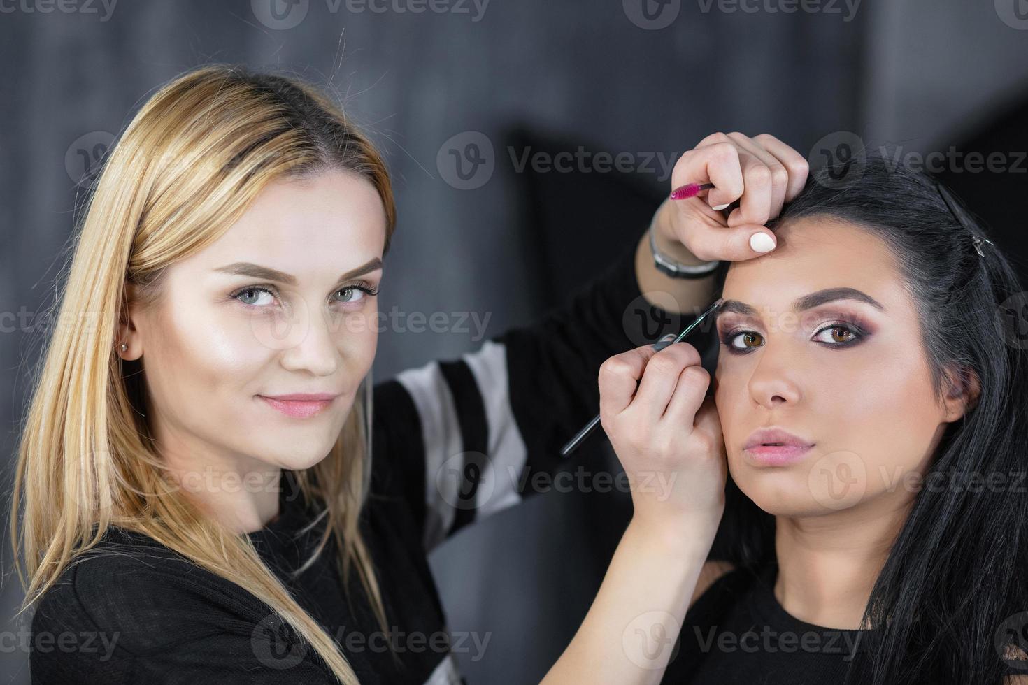 The artist puts a face make up on a nice young model photo