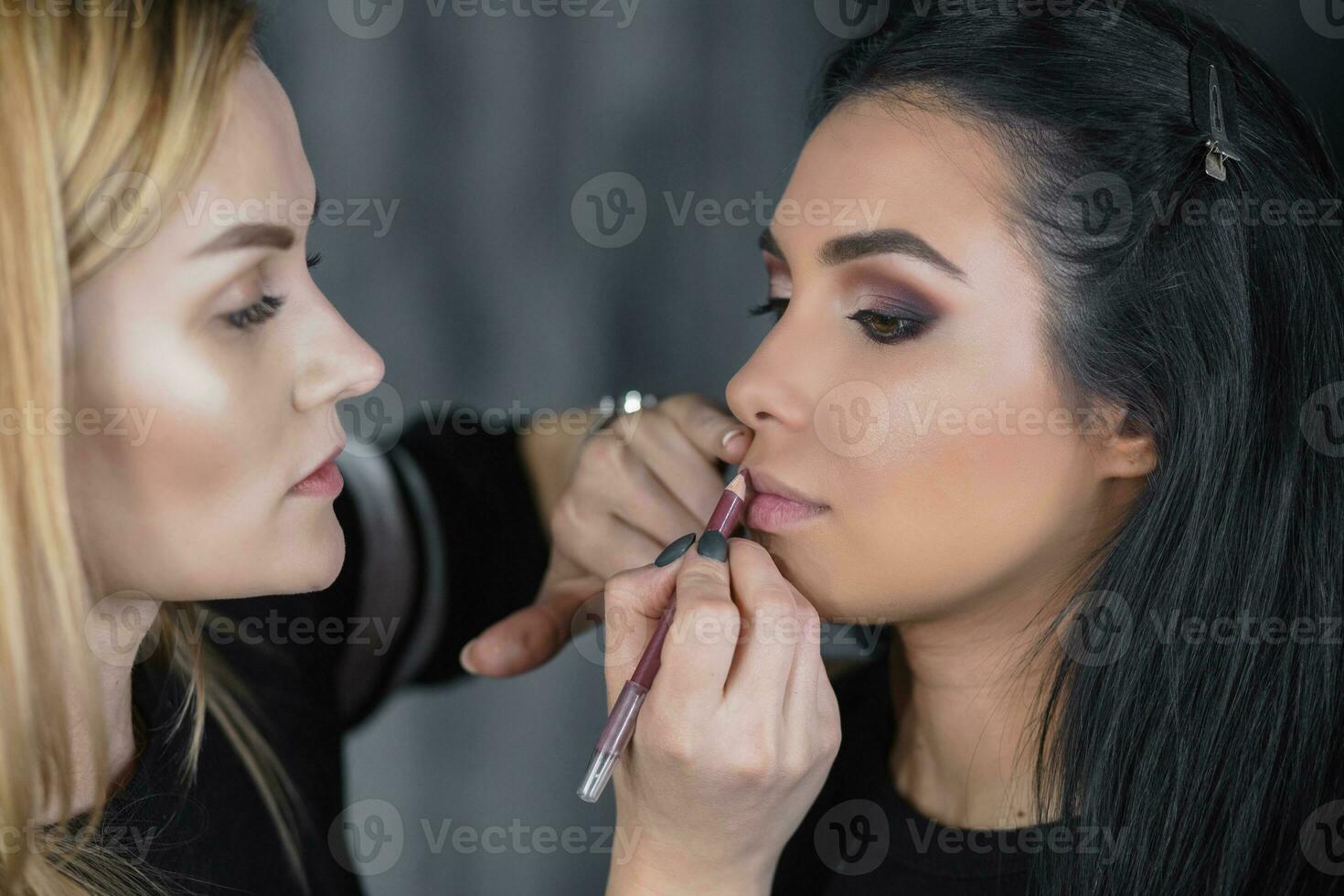 Makeup artist puts a makeup on a young lady photo