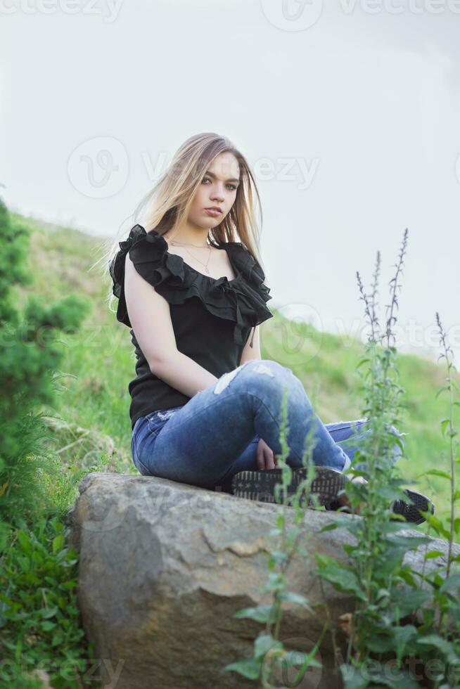 Young pretty woman posing sitting on a stone photo