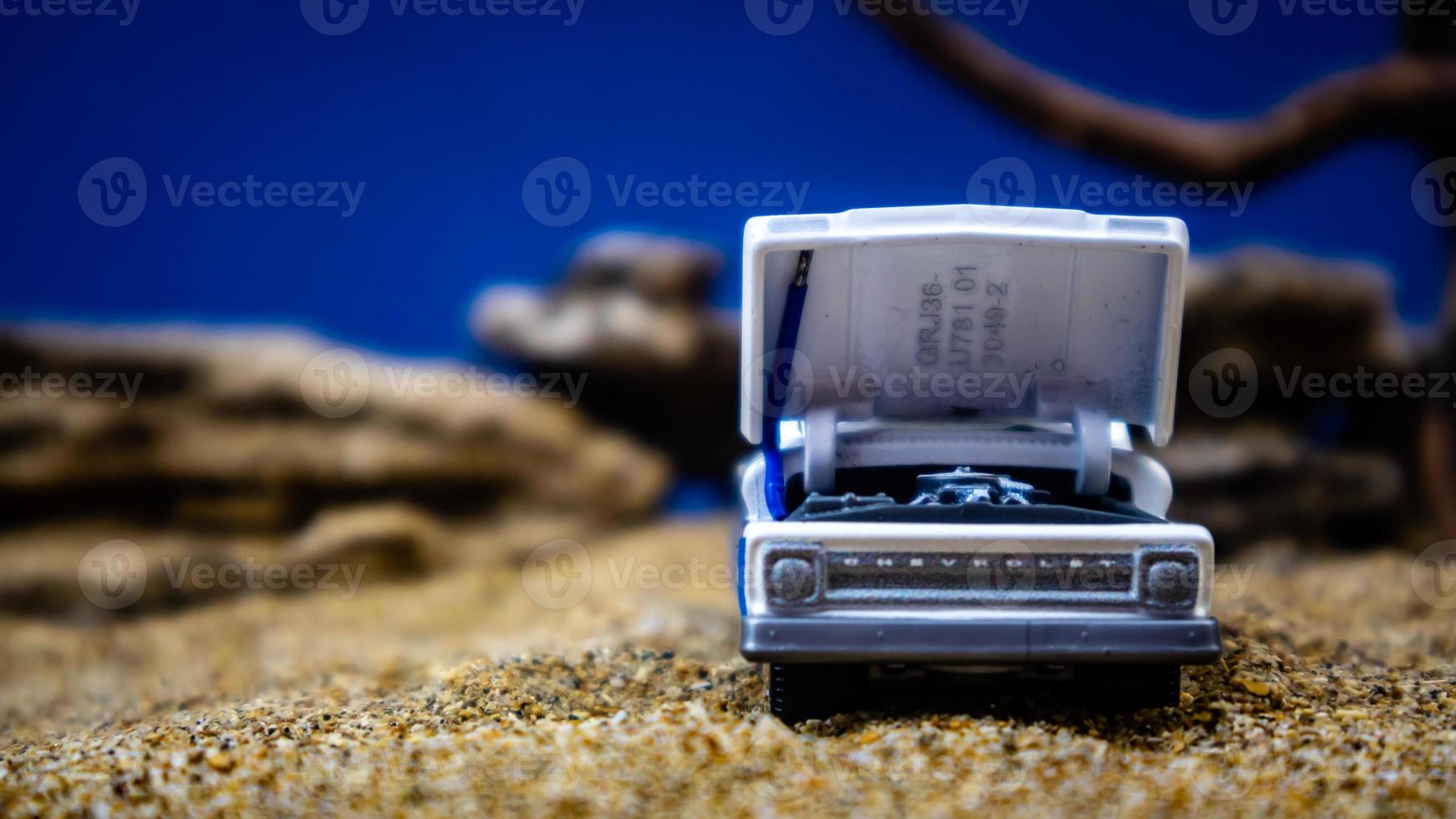 minahasa, Indonesia January 2023, a toy car on the sand with a background of rocks and blue sky photo
