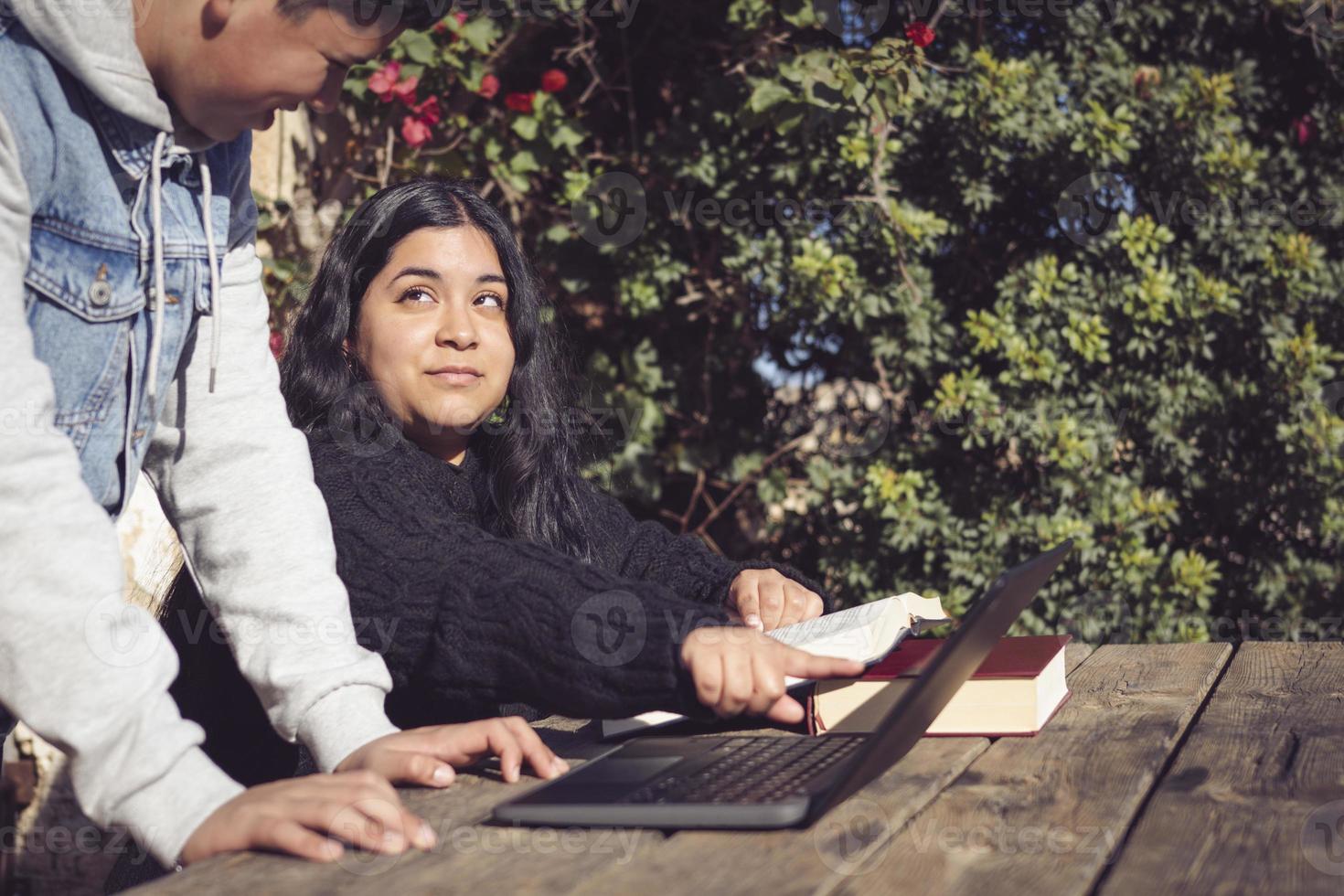 two young men study outside school with laptops photo