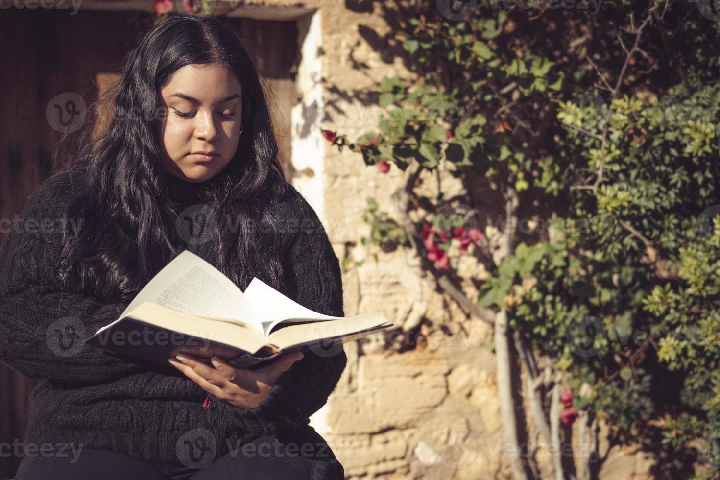 young latin woman sitting reading a book photo