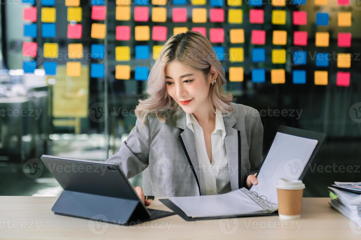 una mujer independiente está trabajando en su trabajo en una tableta de computadora y una computadora portátil haciendo un informe de análisis contable de datos de inversión inmobiliaria, financieros en la oficina foto