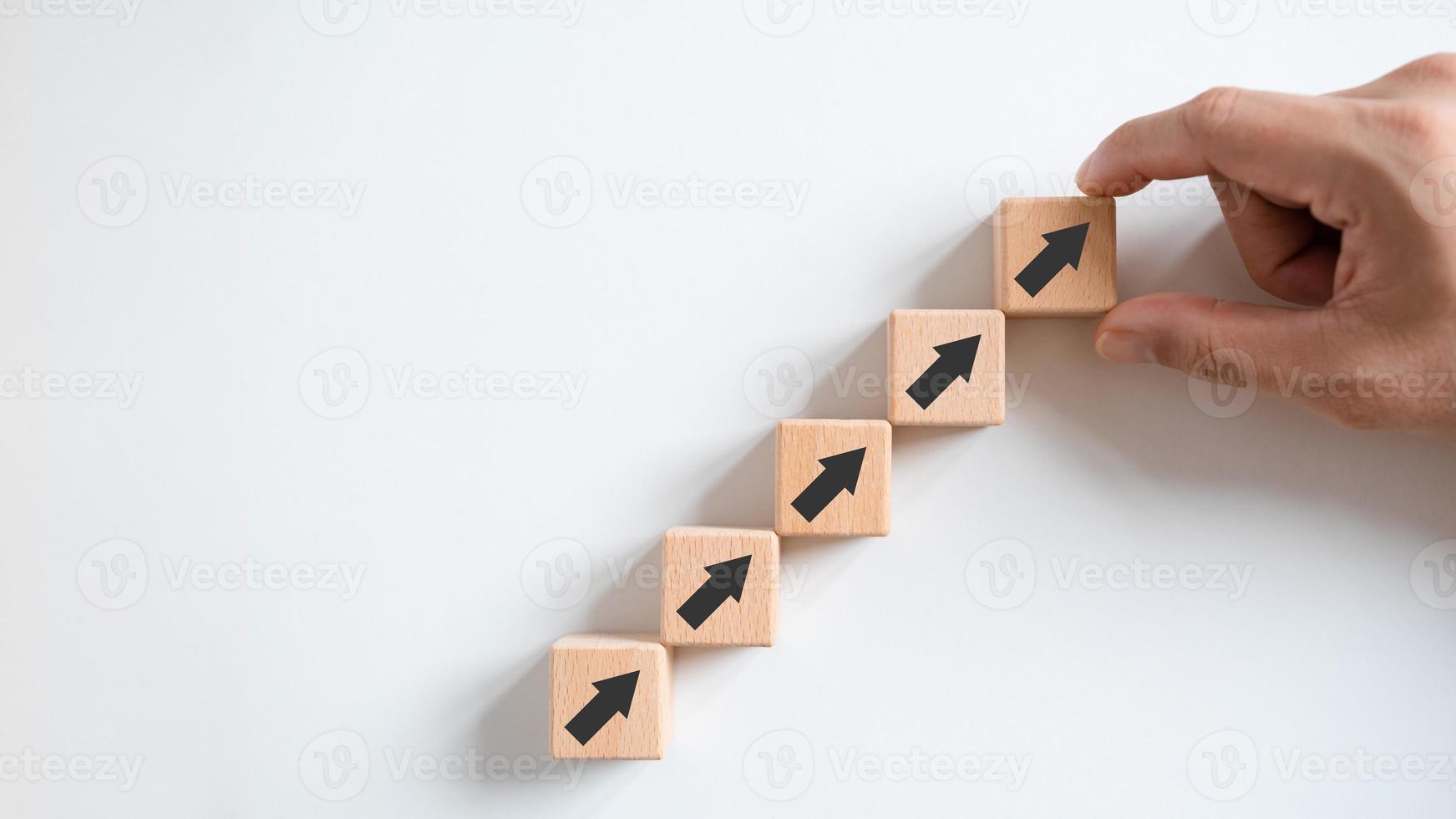 Business growth concept, male hands arranged stacked wooden blocks steps on white table, future business growth arrow, development to achieve goals, copy space. photo