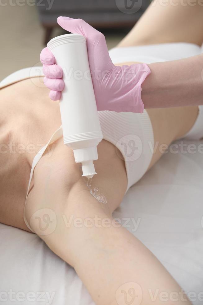 beautician applying guide gel on client's armpits. ipl laser epilation procedure. getting smooth skin in a salon. vertical size photo