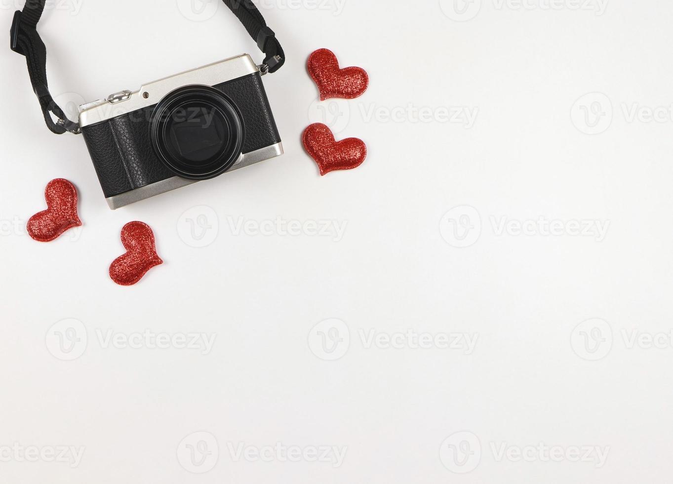 plano laico de digital cámara con rojo Brillantina corazones en blanco antecedentes con Copiar espacio. foto