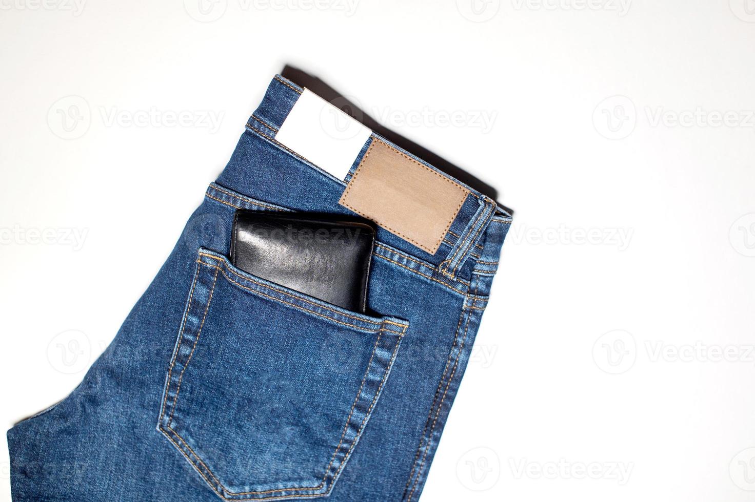 A pair of denim trousers with an empty leather label, a wallet in the back pocket. photo