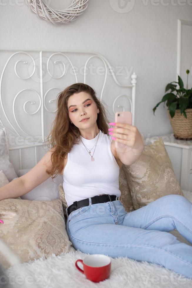 un contento mujer tiene un autofoto el niña mira dentro el teléfono cámara y sonrisas foto