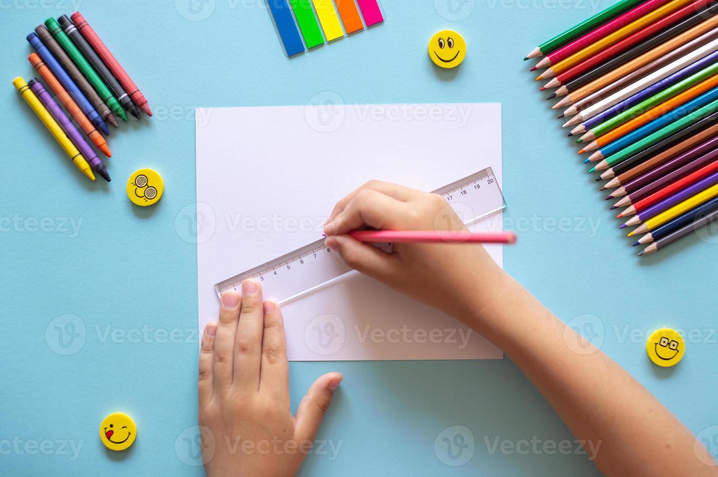 A set of bright stationery on a blue background. Hands holding a ruler photo
