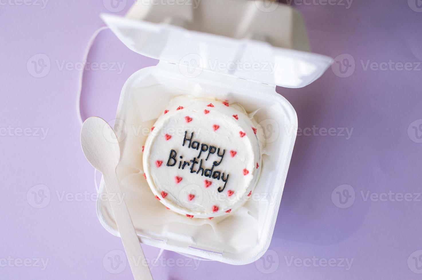un abierto caja con un cumpleaños bento pastel en un púrpura antecedentes foto