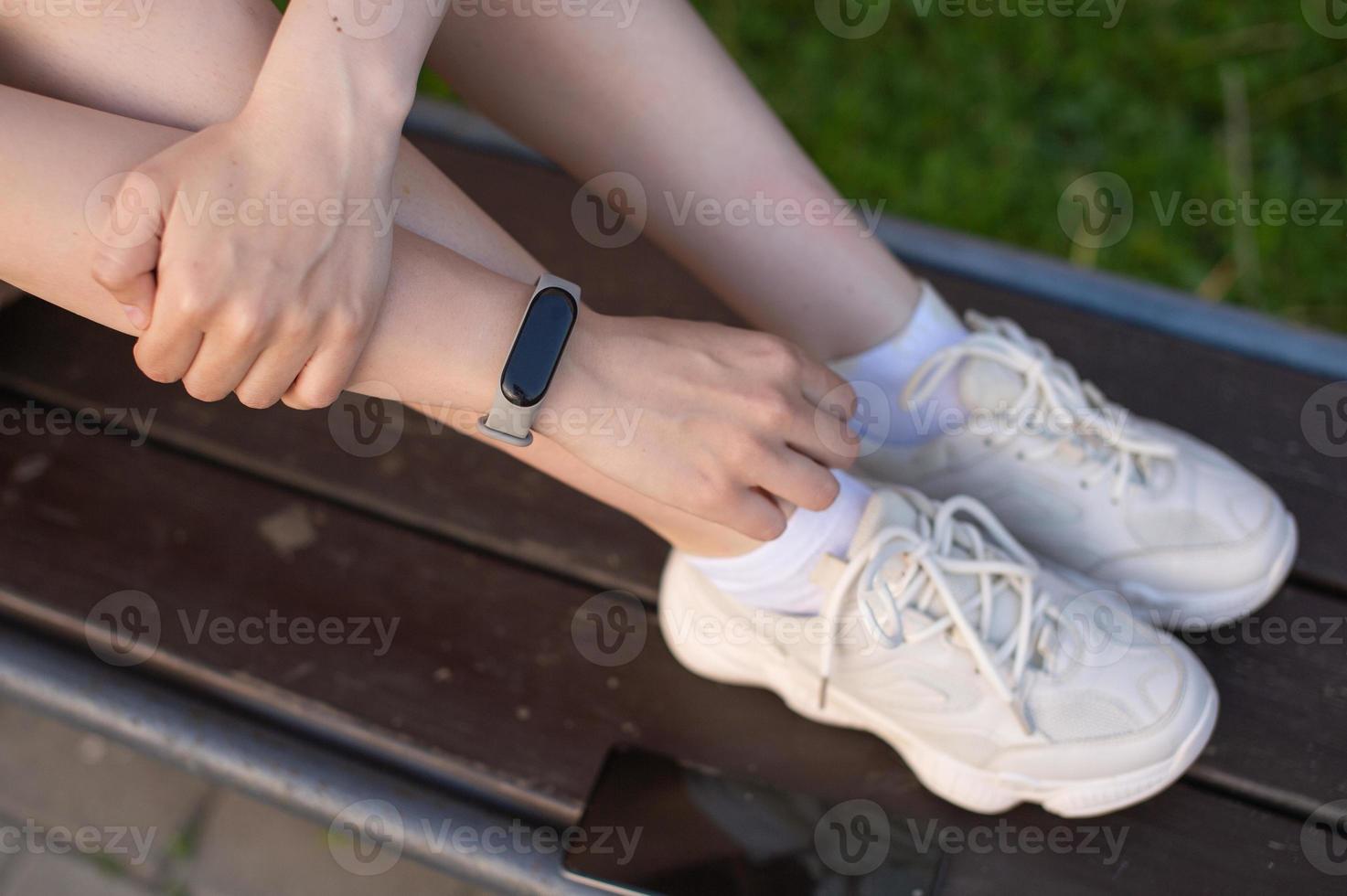 The girl is holding a white phone in her hands, a sports watch on her hand photo