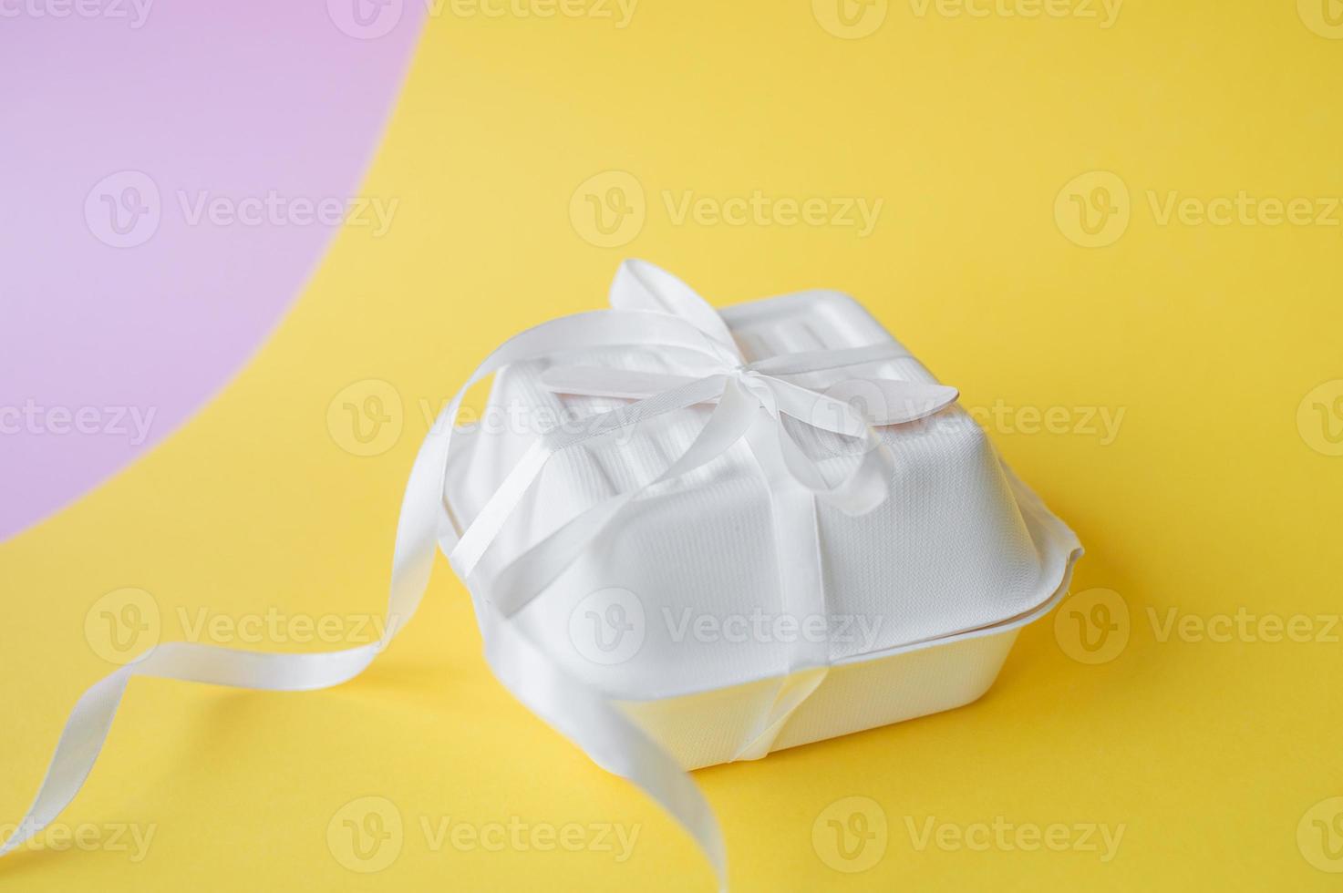 A bento cake box with a wooden spoon stands closed on a yellow background photo