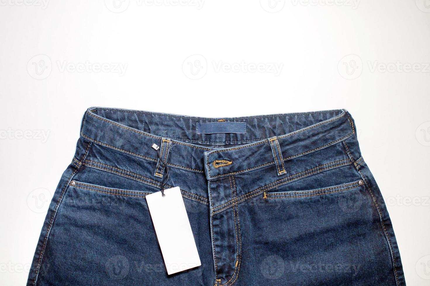 Mock-up of a white card of a clothing tag on denim trousers photo