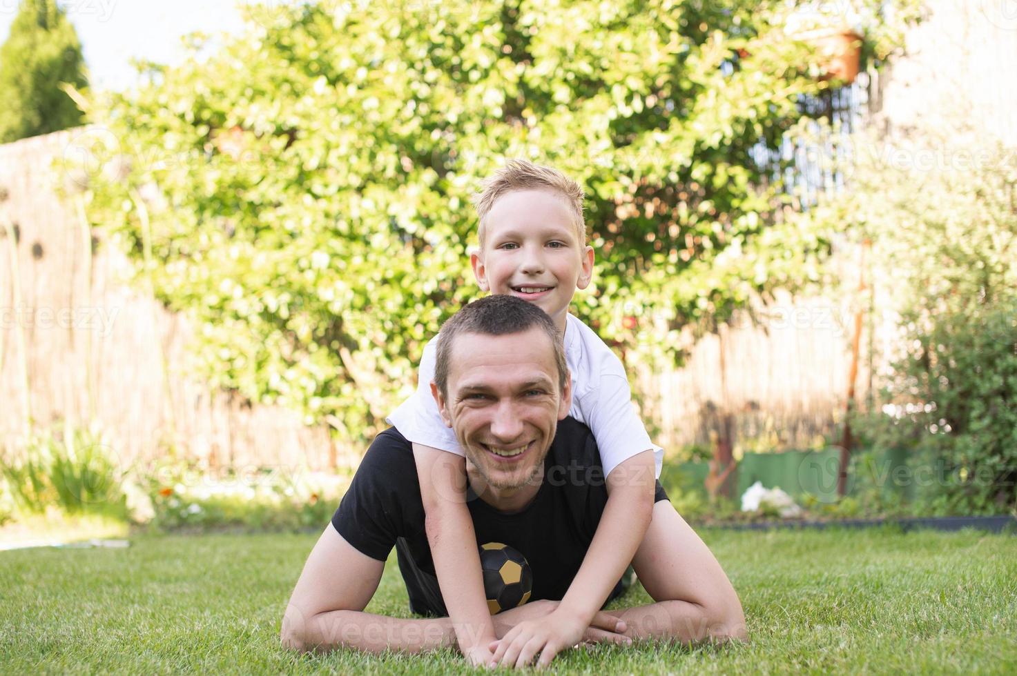 A cute baby is lying on his father's back. Lying on the lawn photo