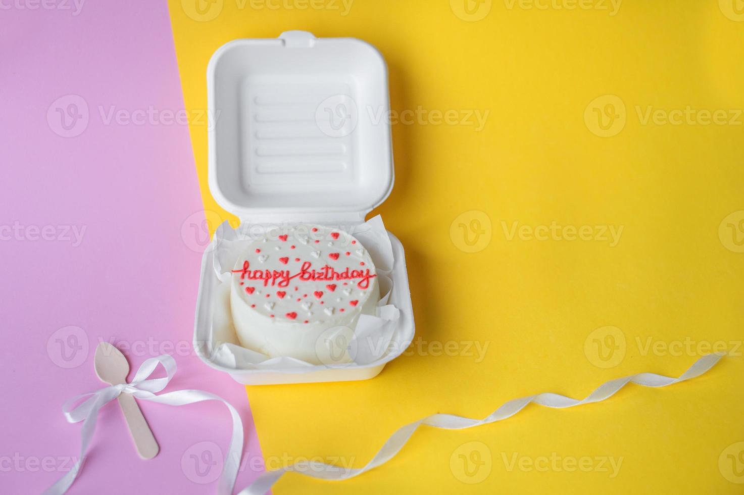 A small bento birthday cake in a box. Wooden boat with white ribbon photo
