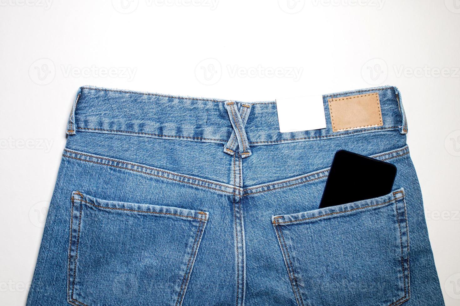 un moderno teléfono en el espalda bolsillo de vaqueros, mostrando el aplicación en un negro pantalla. foto