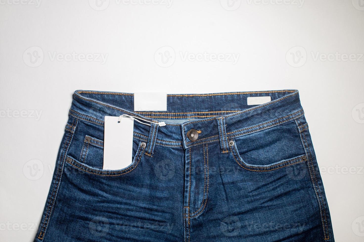 A mock-up of a white price tag card in a denim pocket is a fashionable background, a place to copy. photo