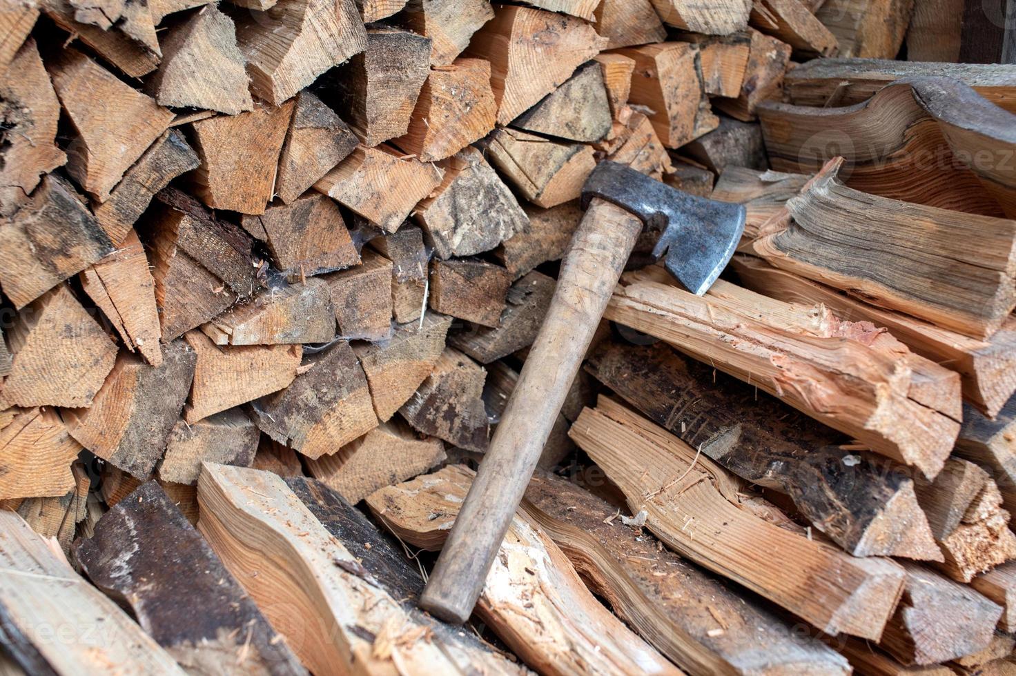 The stacked lumber lies in the woodpile. Axe with wooden handle photo