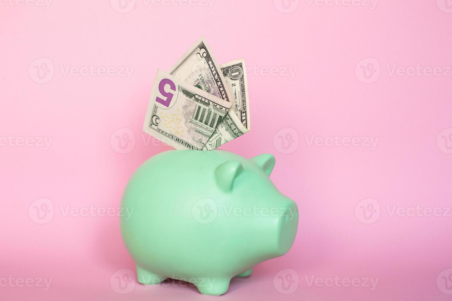 5 and 10 dollar bills on a pink background in a piggy bank photo