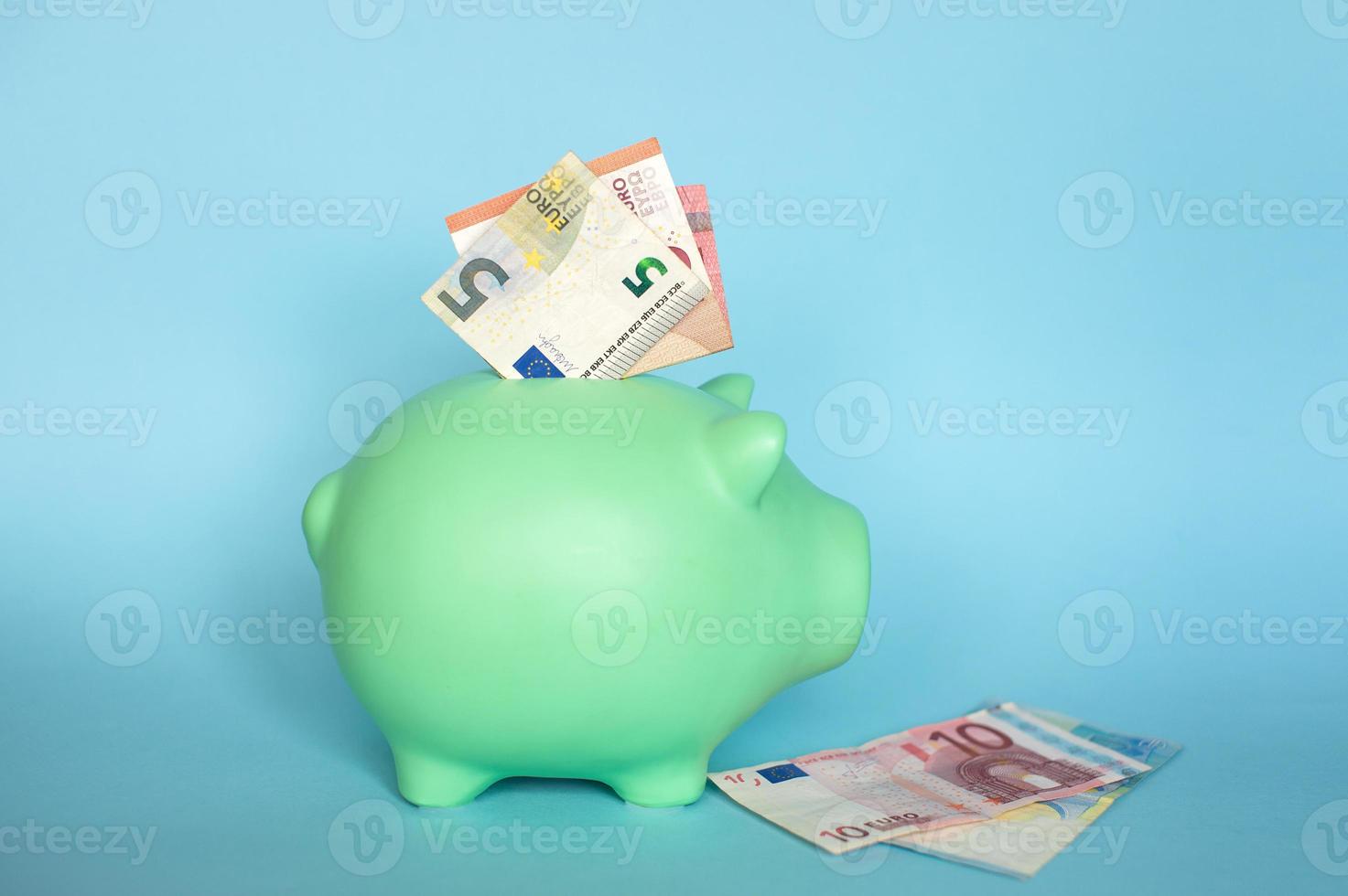 blue piggy bank with 10 and 5 euro notes photo