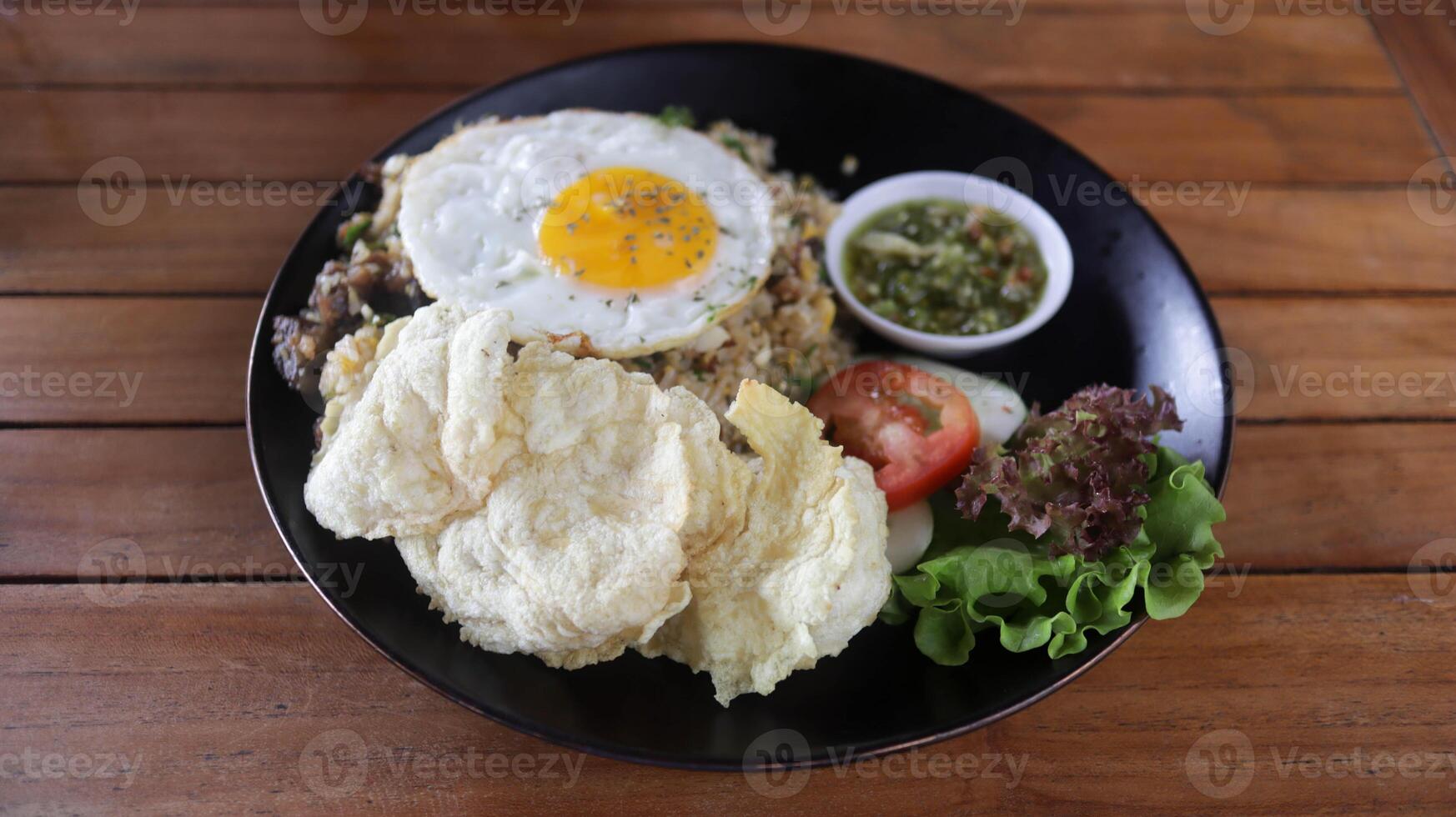 pueblo frito arroz o nasi goreng Kampung hecho con un montón de coberturas, tomate, frito huevo, crujiente, y especial aceitado mezcla chile algunos Fresco vegetal. foto