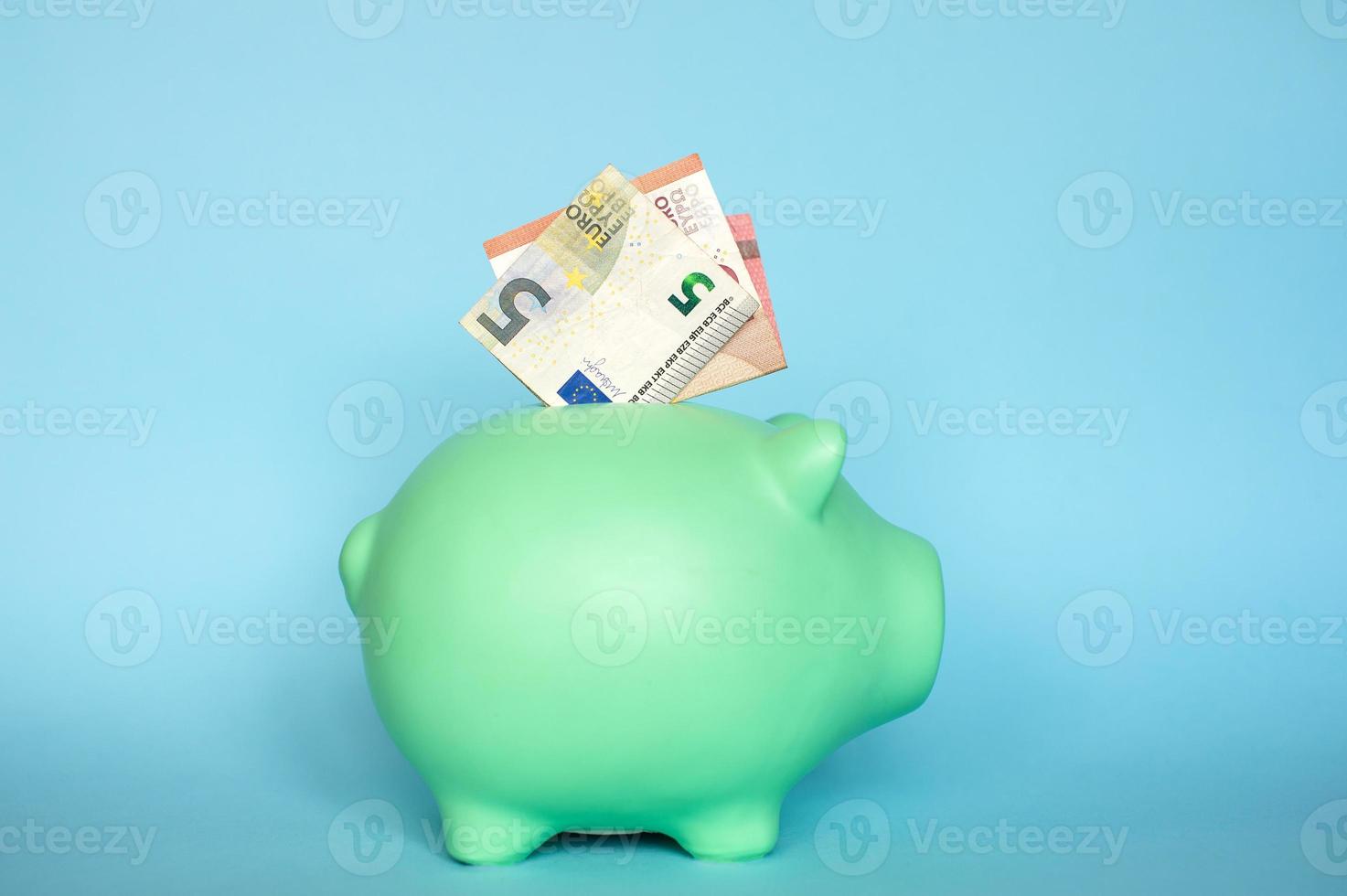 blue piggy bank with 10 and 5 euro notes photo