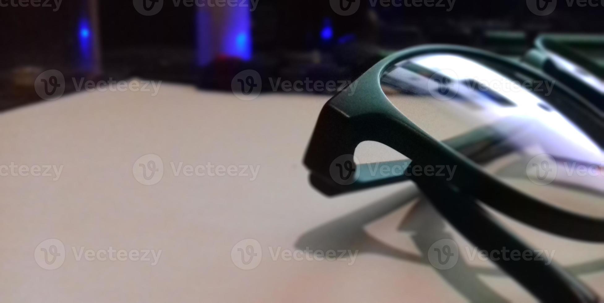 black shiny eye glasses on the desk with reflection photo