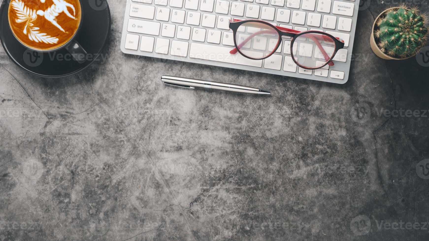 Dark office desk workplace with keyboard computer, eyeglass, pen and cup of coffee, Top view flat lay with copy space. photo