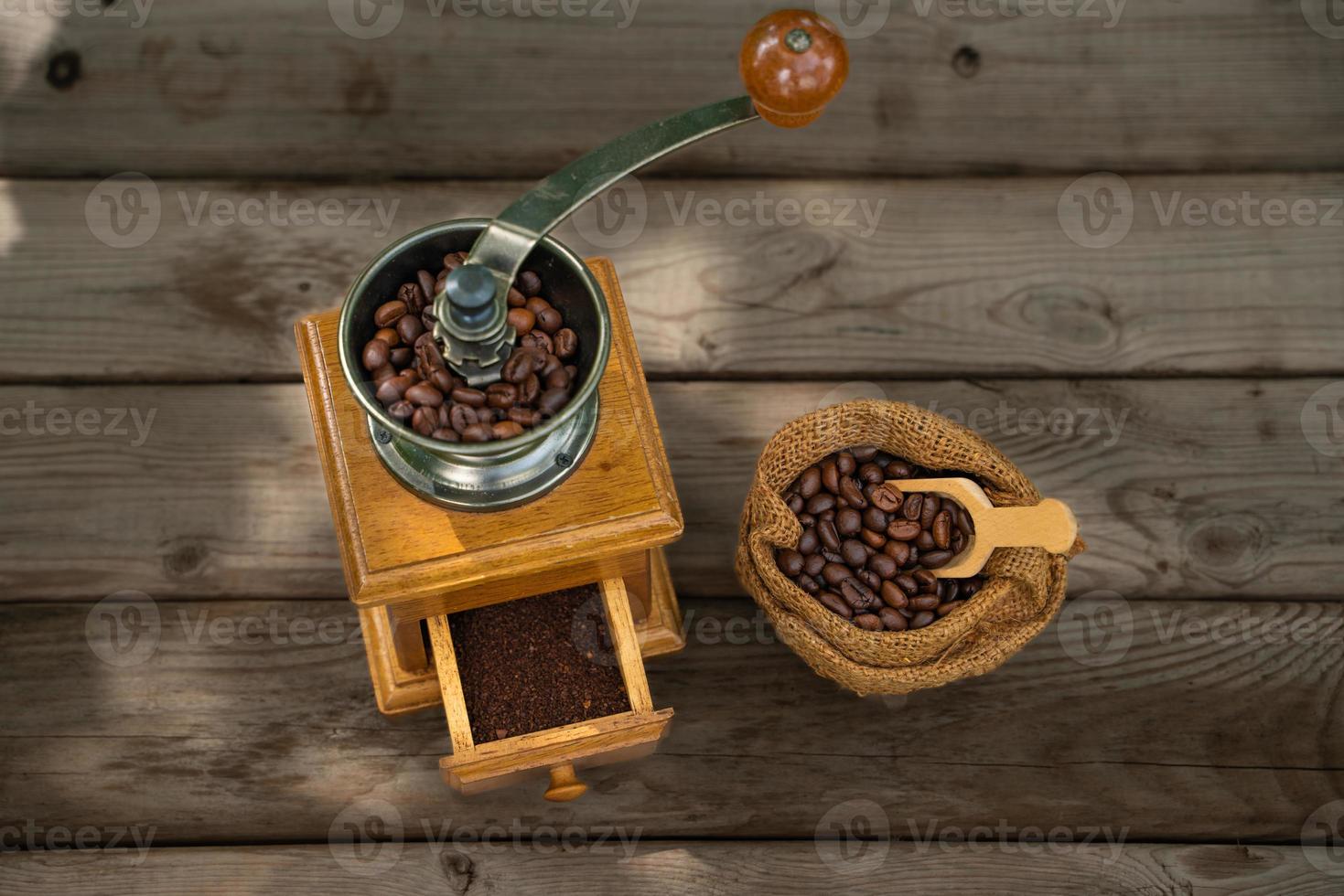 Vintage coffee grinder, Old retro hand-operated wooden and metal coffee grinder.Manual coffee grinder for grinding coffee beans on the old wooden background. photo