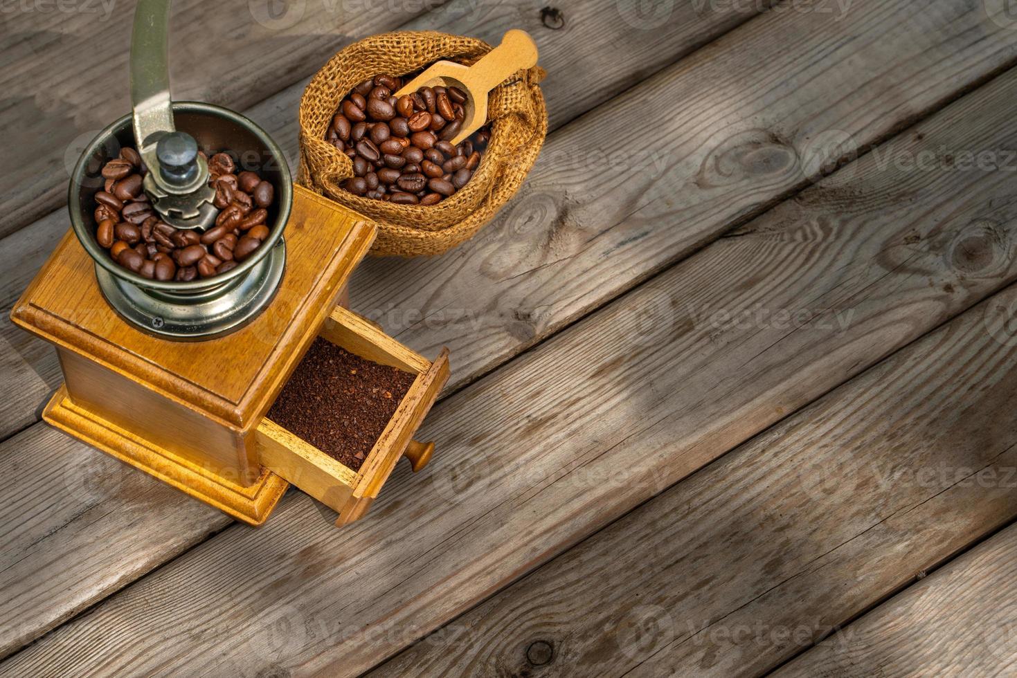 Vintage coffee grinder, Old retro hand-operated wooden and metal coffee grinder.Manual coffee grinder for grinding coffee beans on the old wooden background. photo