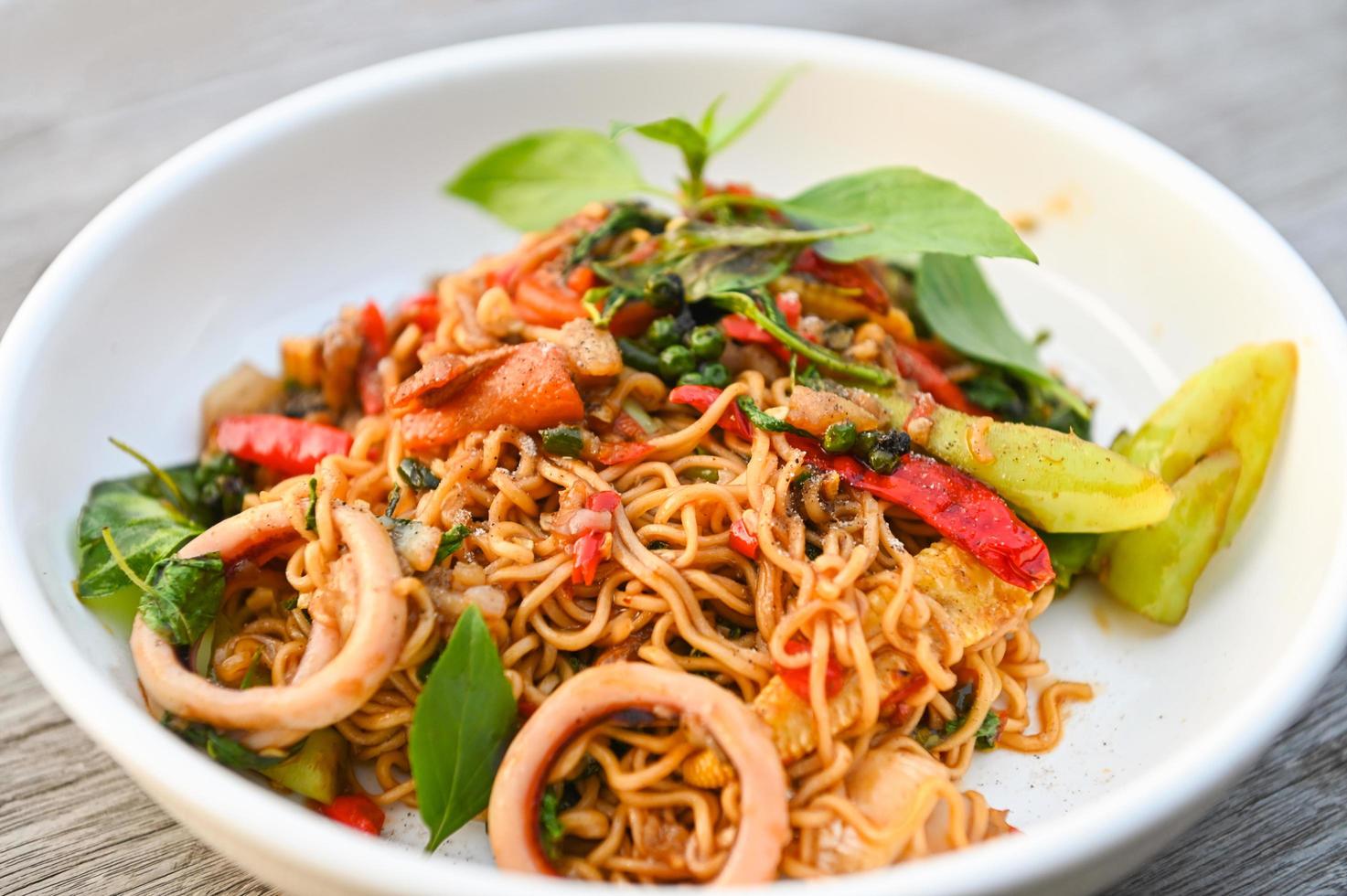 noodles plate with instant noodles stir fried with vegetables herb spicy tasty appetizing asian noodles mix seafood stir fried squid with basil and chilli pepper photo