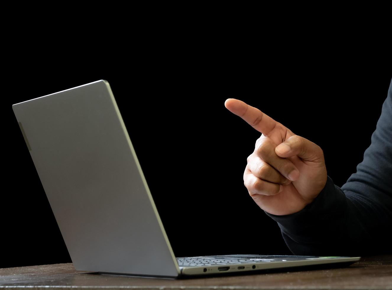 Computer and hands of a man wearing a black shirt, sitting on a chair and a table, is a thief, holding money, counting the amount obtained from hijacking or robbing, in a pitch-black room. photo