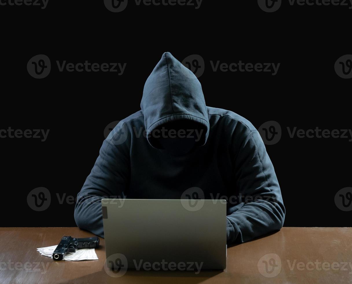 Hacker spy man one person in black hoodie sitting on a table looking computer laptop used login password attack security to circulate data digital in internet network system, night dark background. photo