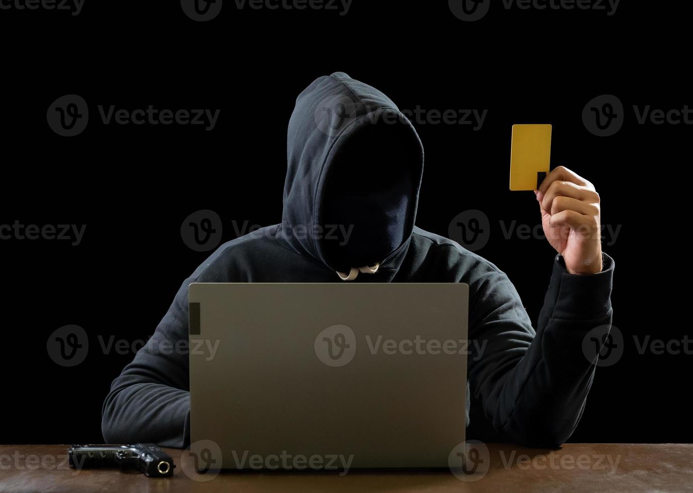 Hacker spy man one person in black hoodie sitting on a table looking computer laptop used login password attack security to circulate data digital in internet network system, night dark background. photo