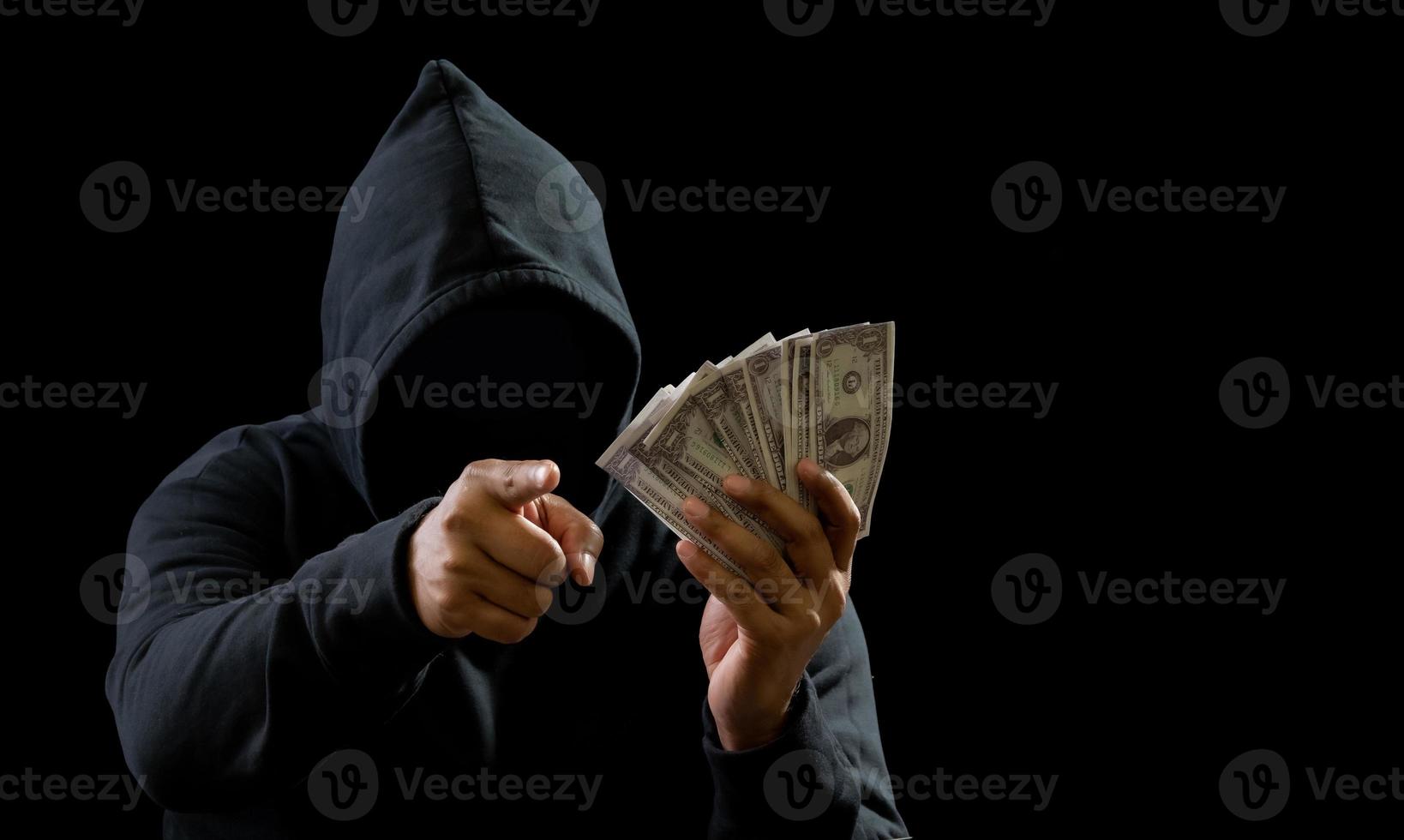 Hacker spy man hands wearing a black shirt, sitting on a chair and a table, is a thief, holding money, counting the amount obtained from hijacking or robbing, in a pitch-black room. photo
