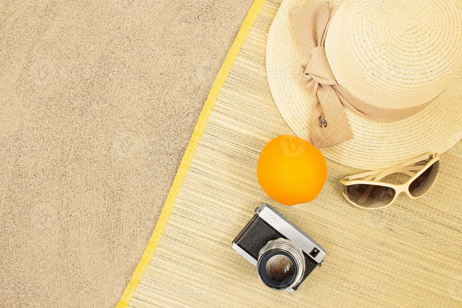 Straw hat with orange, sunglasses, camera on sunbed on beach sand. Rest, travel. Vertical and horizontal. Copy space photo